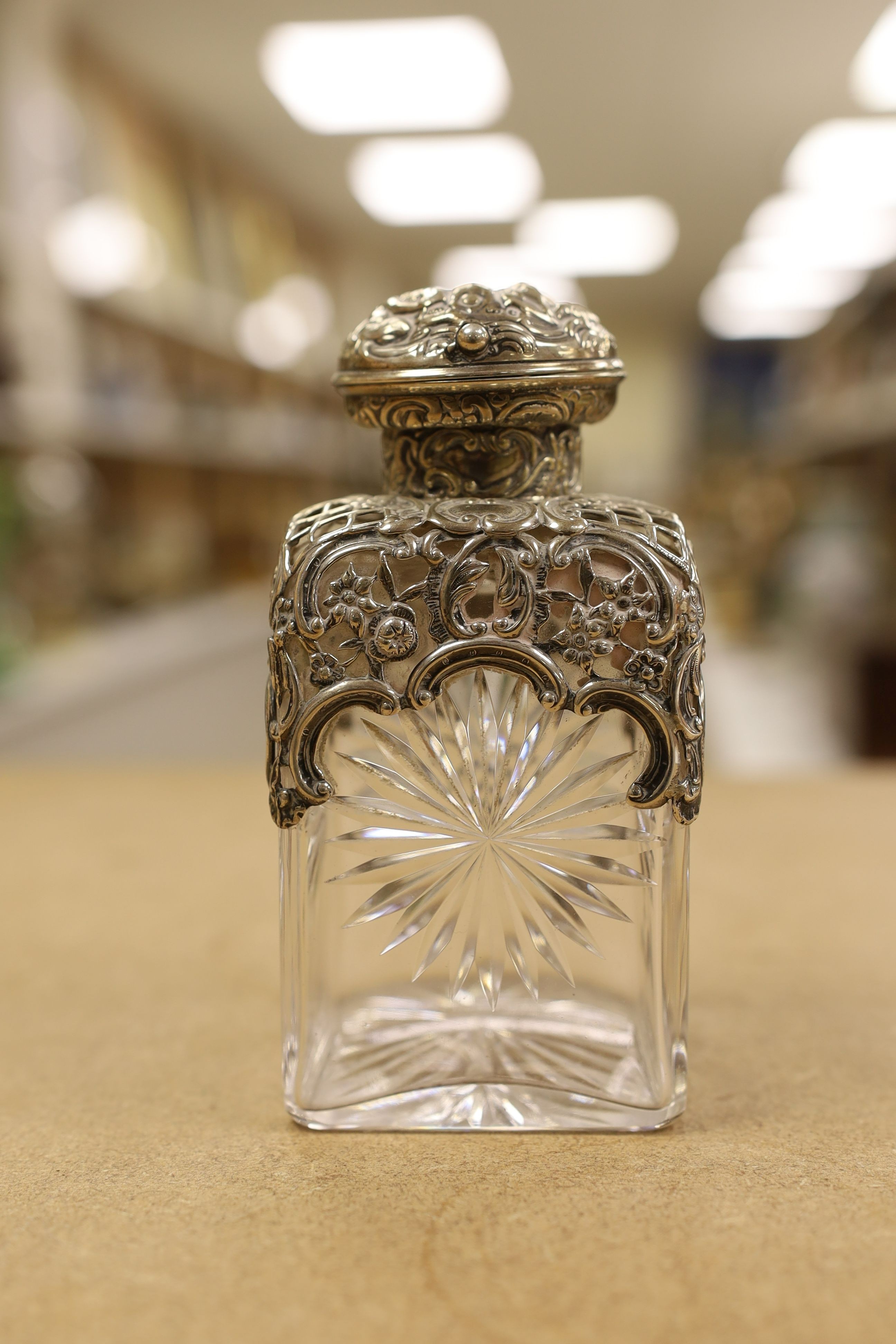 A pair of late Victorian repousse silver mounted cut glass scent bottles with stoppers, William Comyns, London, 1898, height 14.3cm.